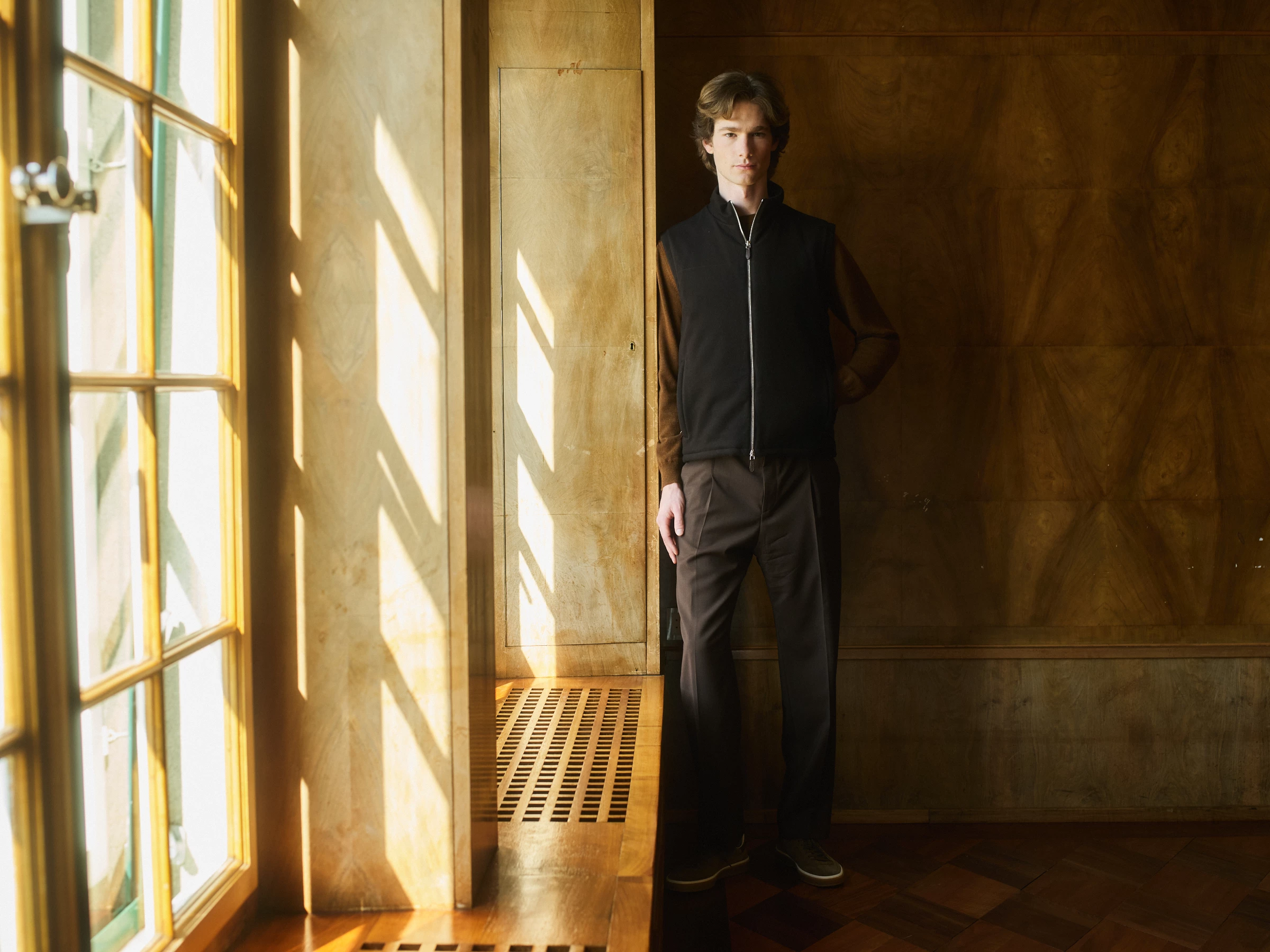 A man standing in a bright room with wooden walls
