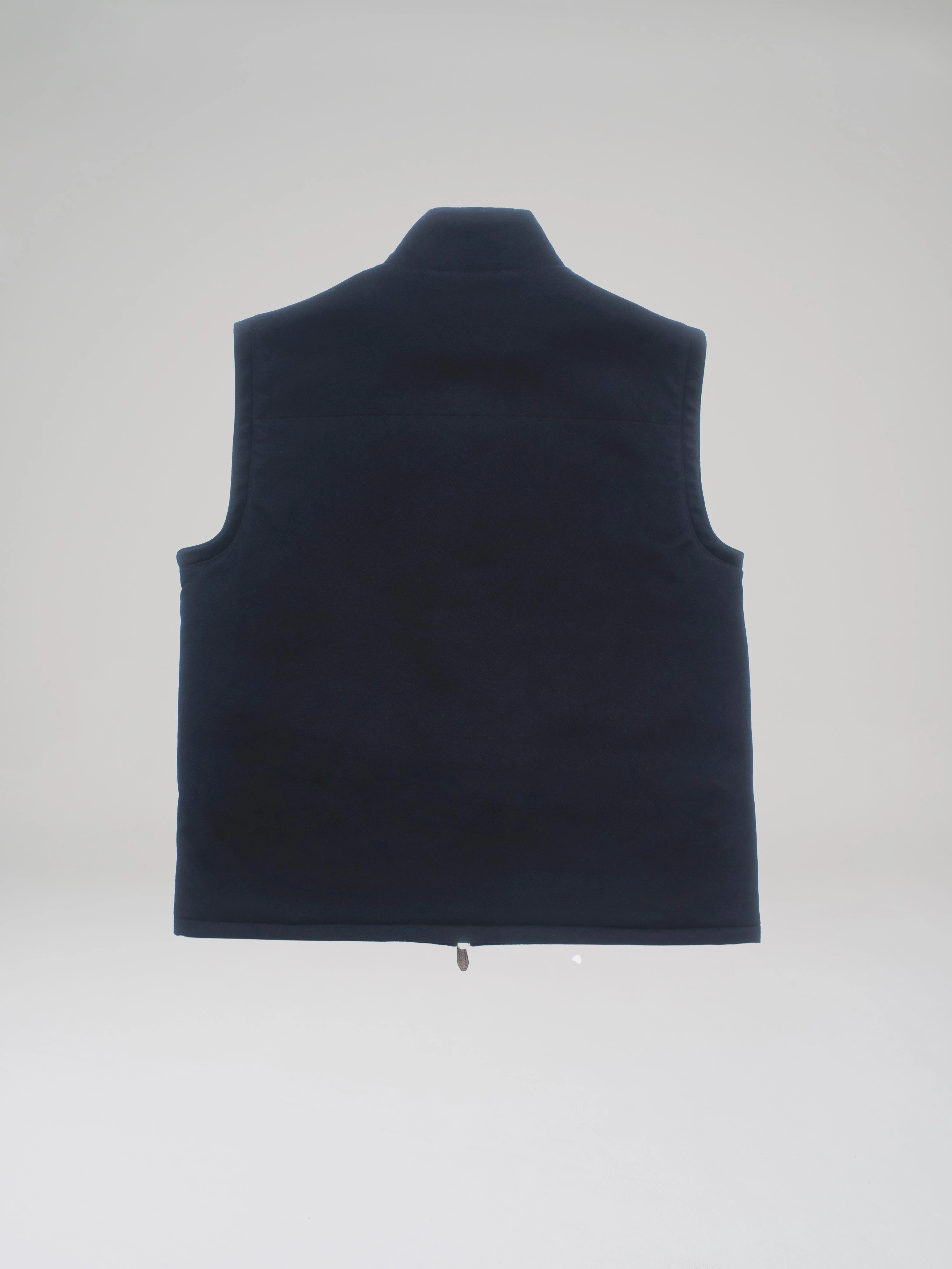 Product shot: back view of a dark blue cashmere bulletproof vest in a studio on a light grey background.
