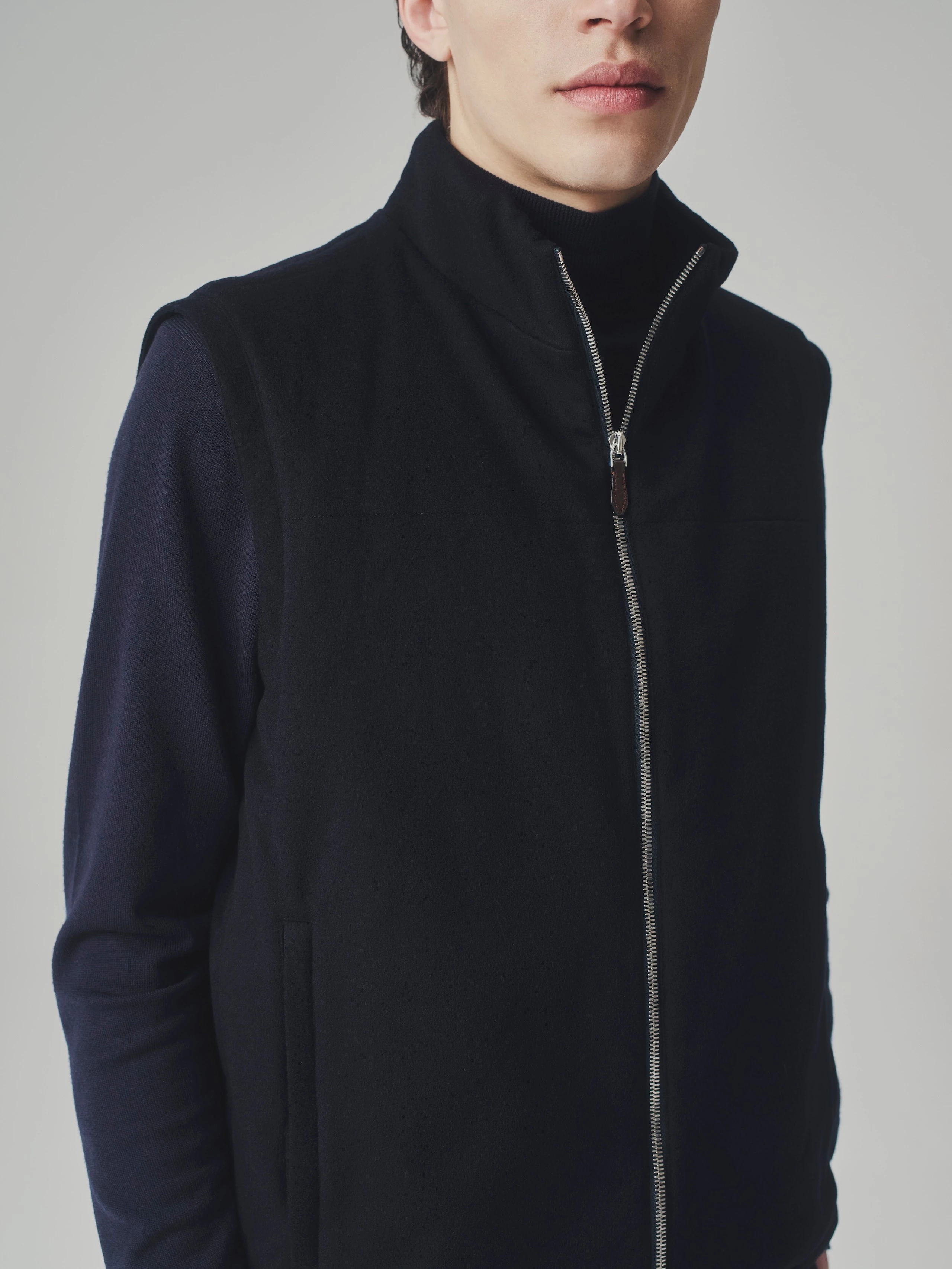 Close-up crop in a studio showing a dark blue cashmere bulletproof vest and cashmere sweater.