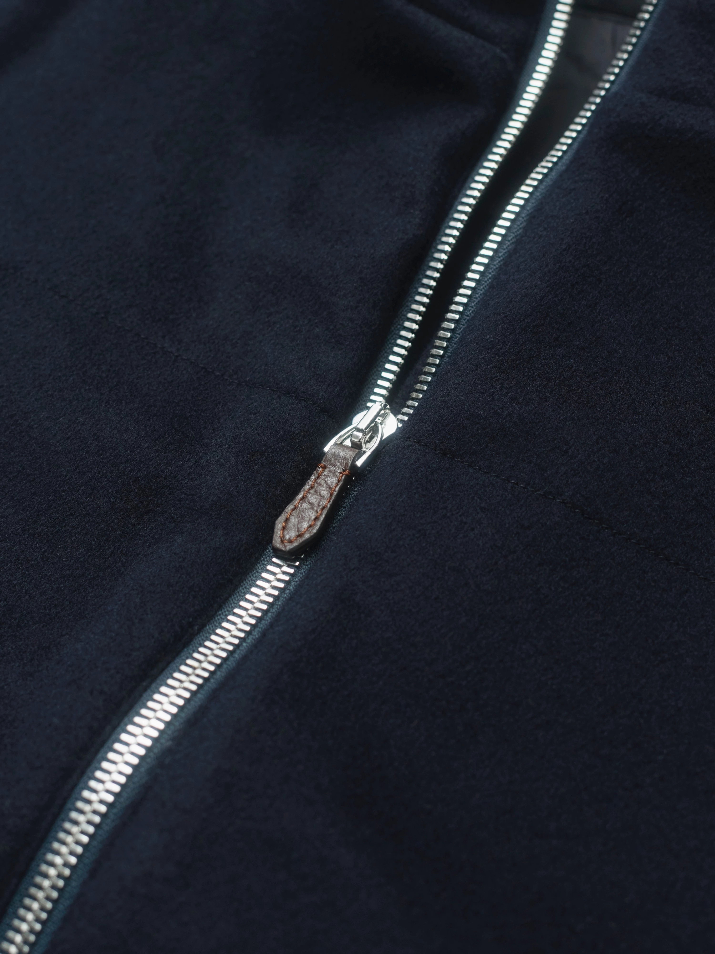 Close-up of a dark blue jacket made of cashmere with a shiny metal zipper.