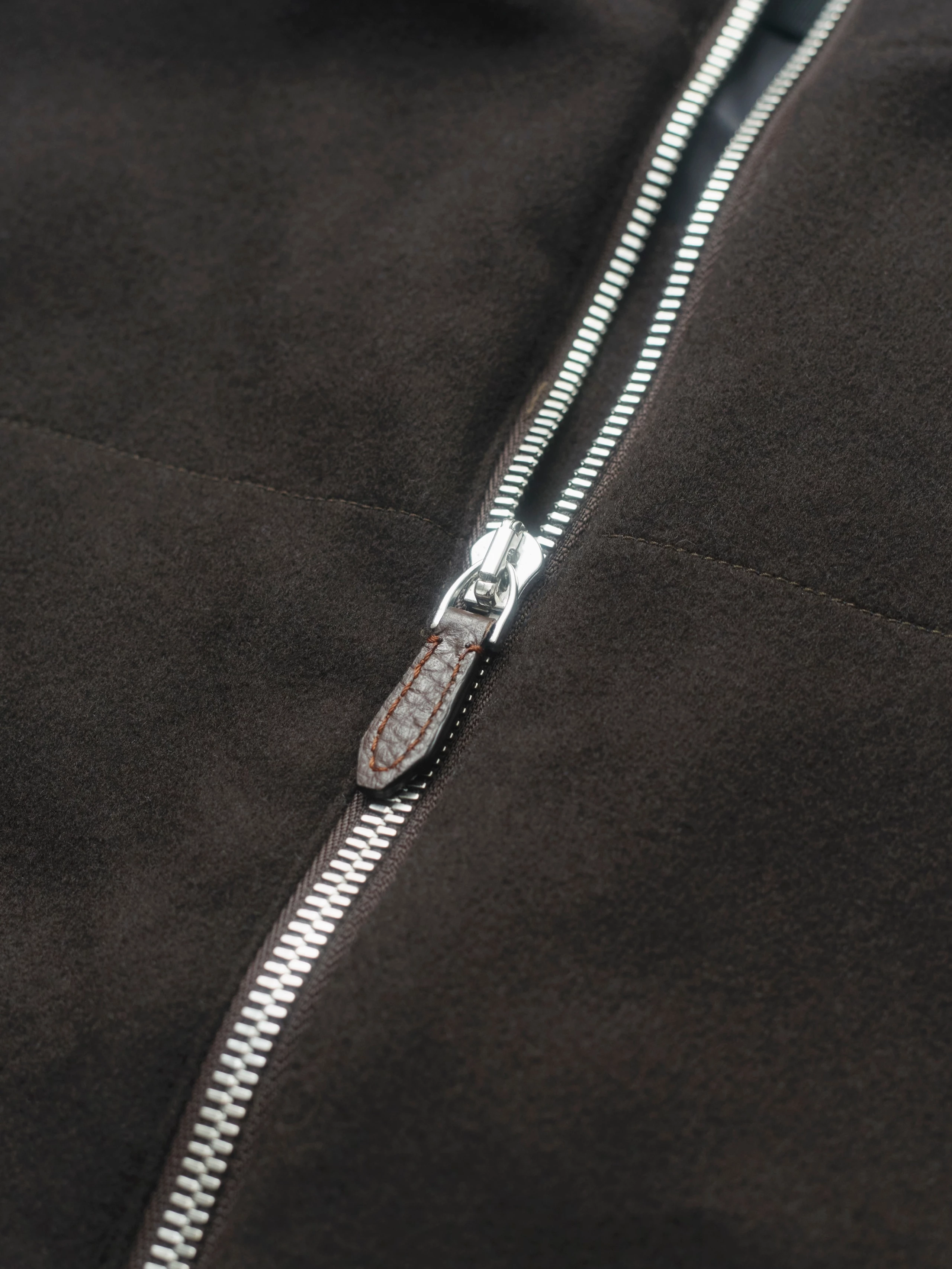 Close-up of a dark brown jacket made of doeskin wool with a shiny metal zipper.